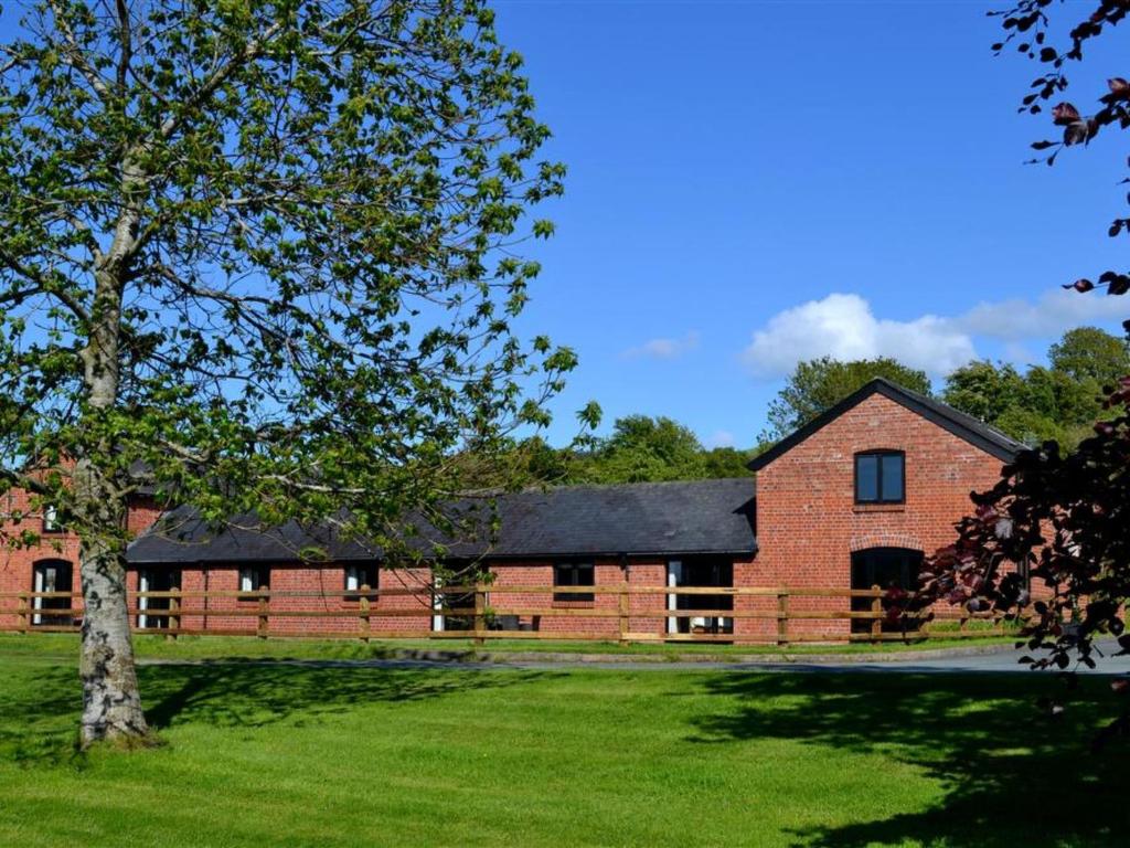 a red brick building with a black roof at Holiday Home Corlan by Interhome in Llandinam