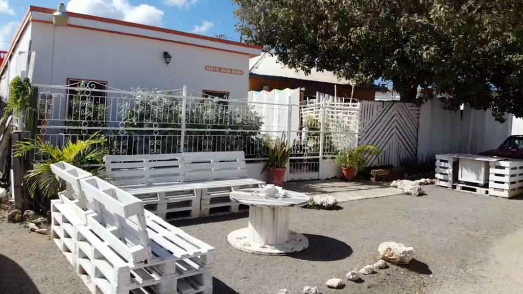 a white bench in front of a white building at Hostel Room Aruba in Oranjestad