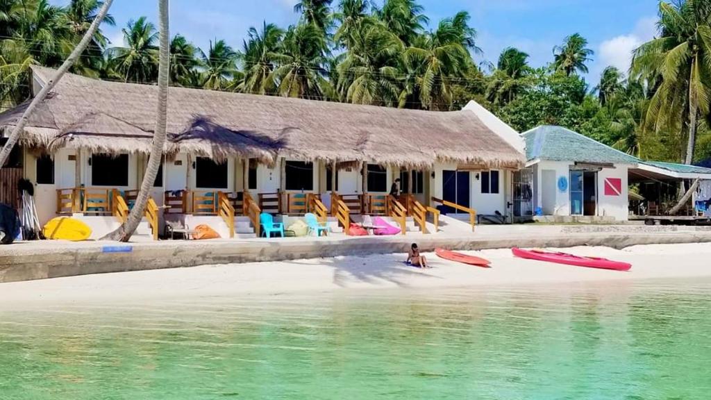 a house on a beach with surfboards in the water at Tropical Fun Ta Sea Rentals in Siquijor