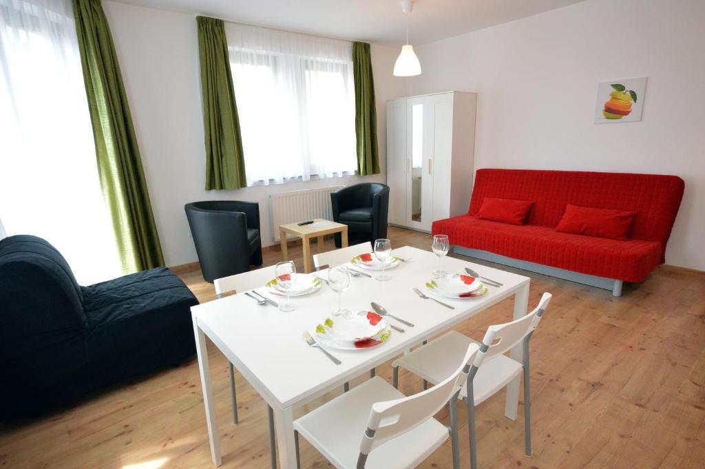 a living room with a white table and a red couch at Toldi Apartments Pécs in Pécs