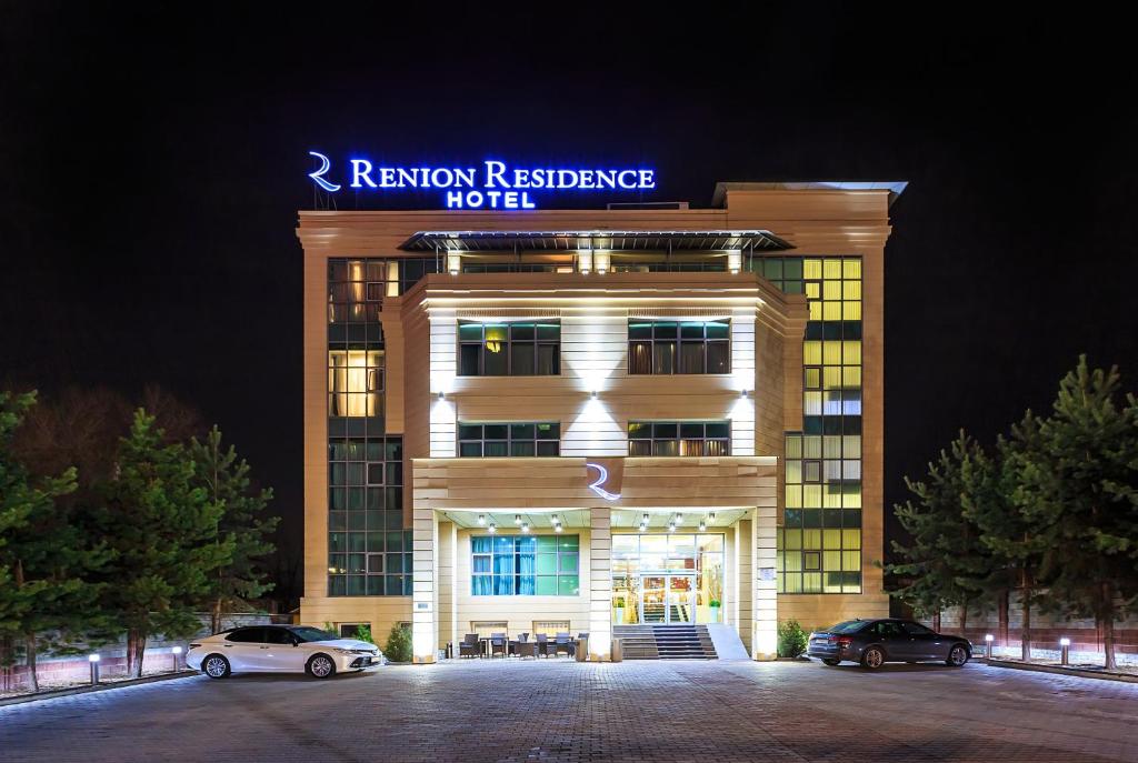 a building with two cars parked in front of it at Renion Residence Hotel in Almaty