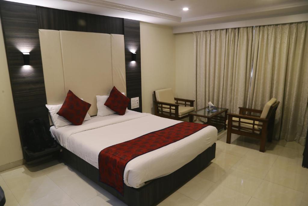 a hotel room with a bed and a table and chairs at Venkat Presidency in Navi Mumbai