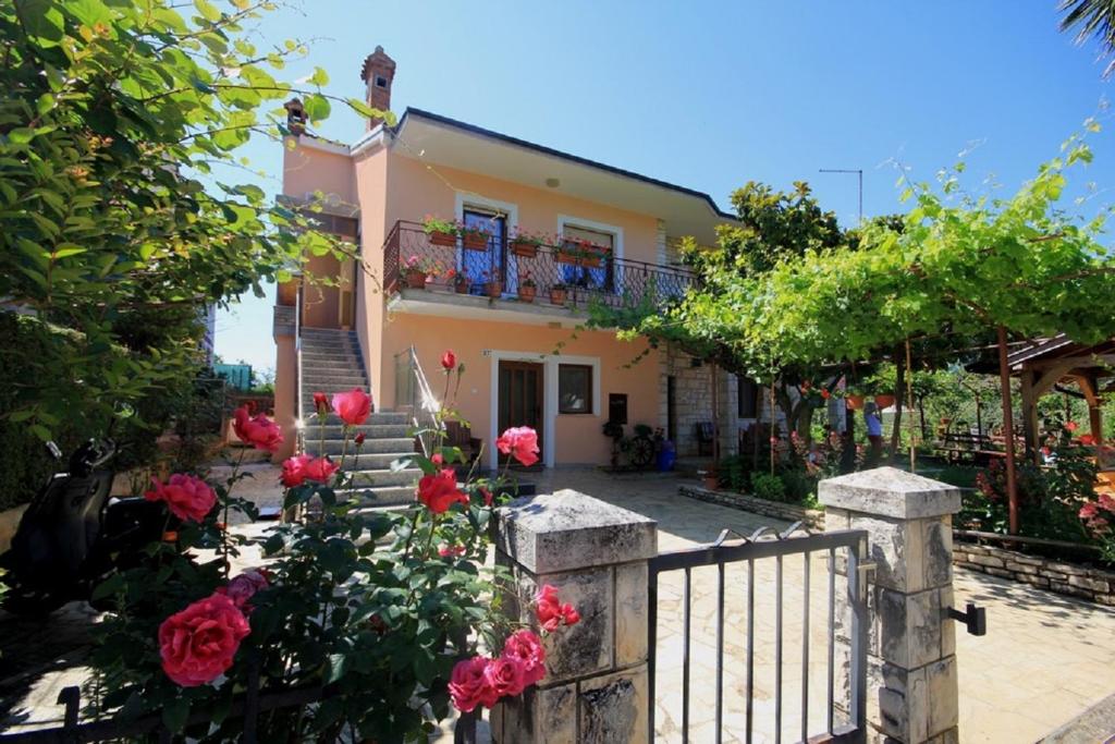 a house with a fence and roses in front of it at Sonja-Dajla Apartments in Dajla