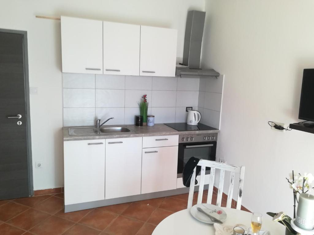a kitchen with white cabinets and a table and a chair at Guesthouse Porec in Poreč