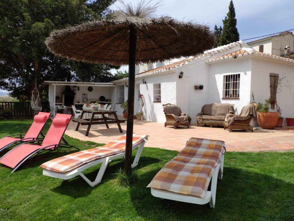 een patio met 2 ligstoelen en een parasol bij Casa Molina in Alcaucín