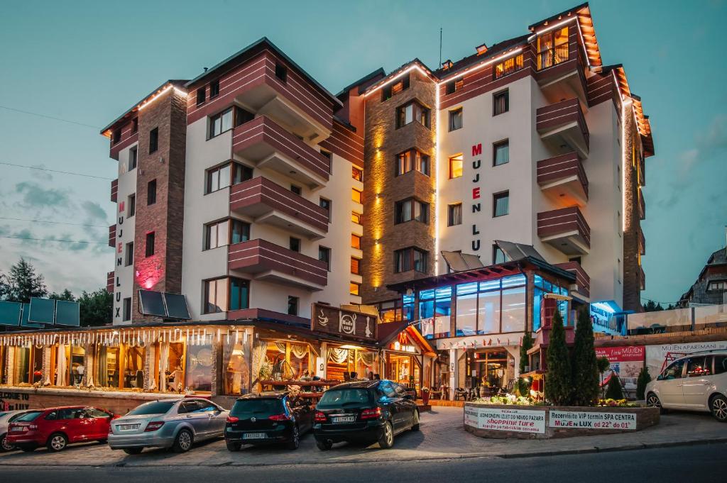 a building with cars parked in a parking lot at Hotel MUJEN LUX Wellness & Spa in Kopaonik