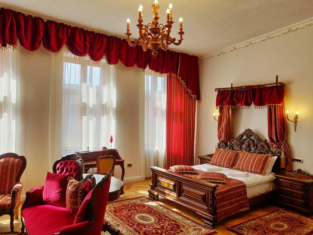 een slaapkamer met een bed met rode gordijnen en een kroonluchter bij Zur Krone in Sibiu