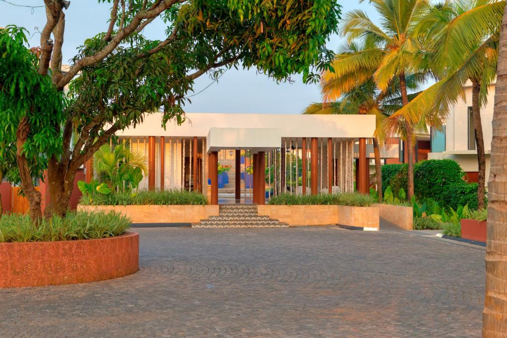a building with palm trees in front of it at Azaya Beach Resort Goa in Benaulim