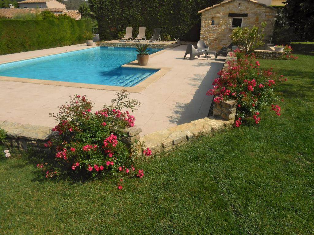 a swimming pool with pink flowers in a yard at GITE L'ATELIER in Palus