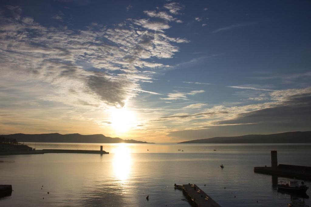 einen Sonnenuntergang über einem Wasserkörper mit einem Pier in der Unterkunft Studio apartman Dida Bozo in Senj