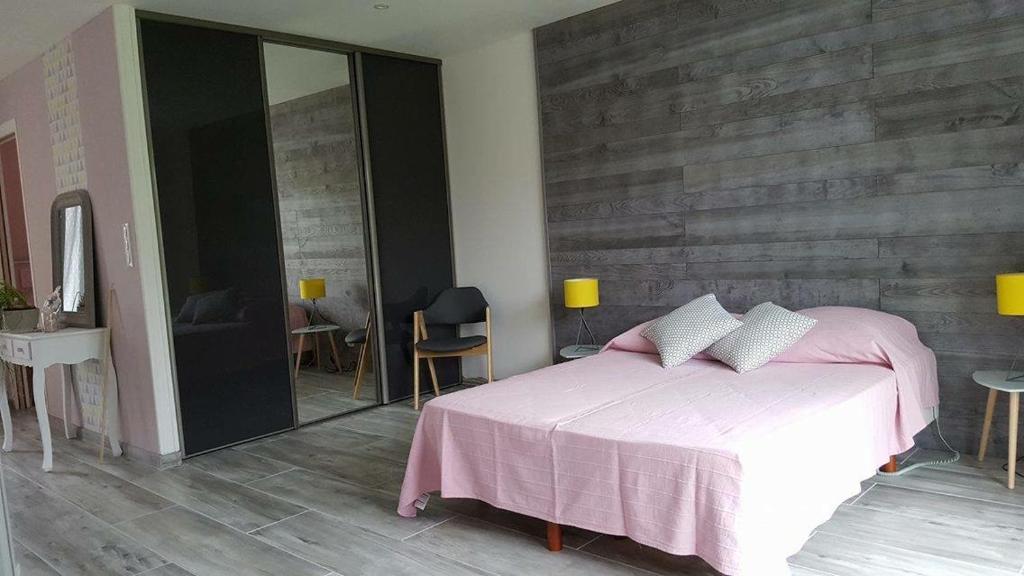 1 dormitorio con cama rosa y pared de madera en La Petite Mer, en Riantec