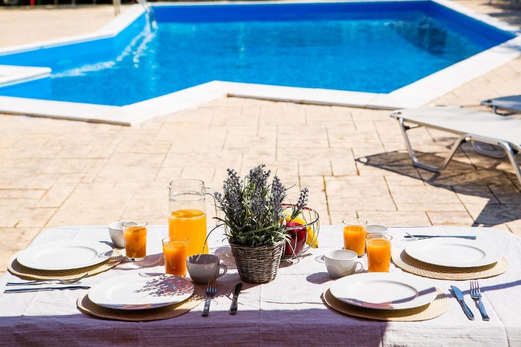 a table with plates and glasses of orange juice at Olive Grove Poolside Apartments in Benitses