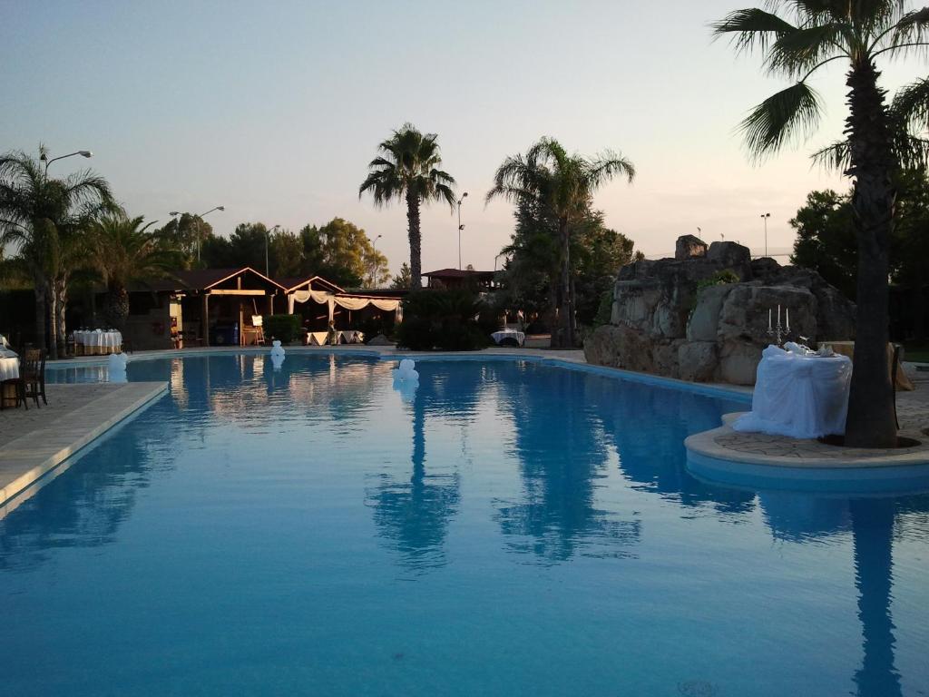 a large swimming pool with palm trees in a resort at Villaggio Turistico Malibuù in Manduria