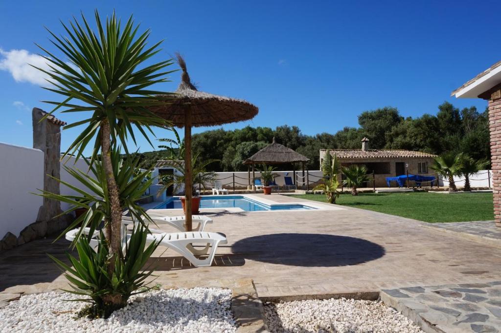 un patio con una silla, una sombrilla y una piscina en Villa fuente redonda en Barbate