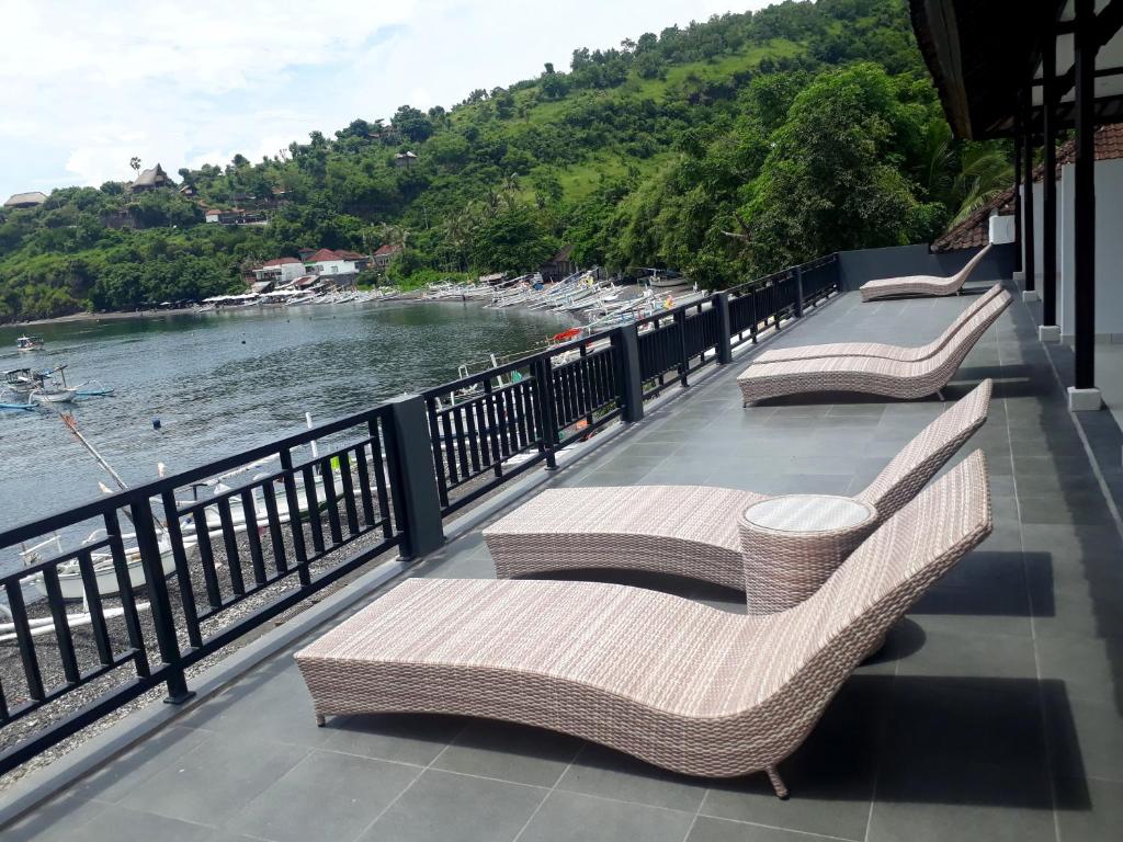 three wicker benches sitting on a balcony overlooking the water at Galang Kangin Bungalows in Amed