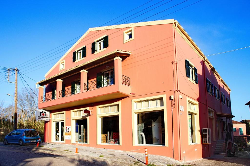 un edificio arancione con balcone su una strada di Darmani Spyros Apartments a Mantoúkion