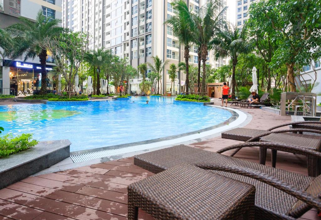 une grande piscine avec des bancs et des palmiers dans une ville dans l'établissement Vinhomes Premium Apartment, à Hô-Chi-Minh-Ville
