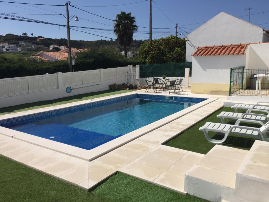 a swimming pool in a yard with chairs and a table at Casa Vila Sao & Pompeia in Sesimbra