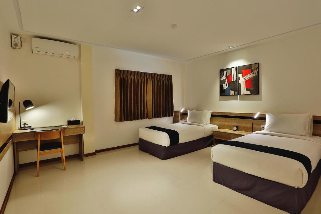 una camera d'albergo con due letti e una scrivania di K.C Hotel a Yangon