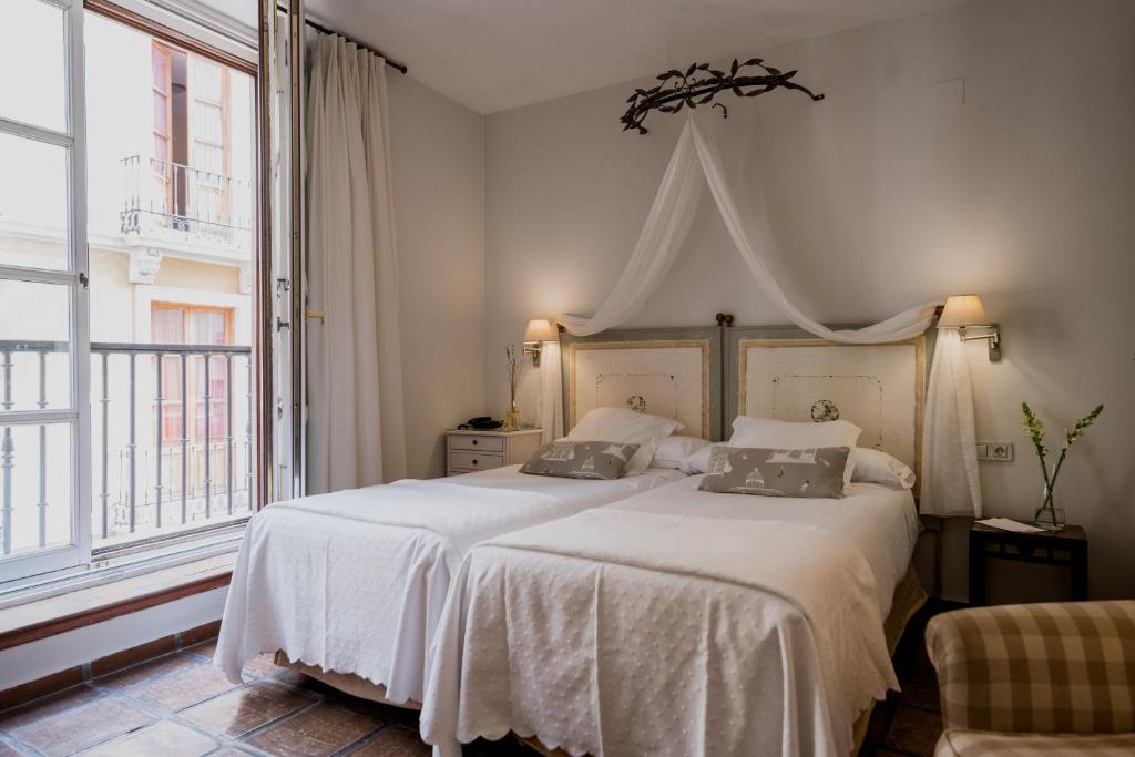 a bedroom with a large white bed with two pillows at Palacio De Los Navas in Granada