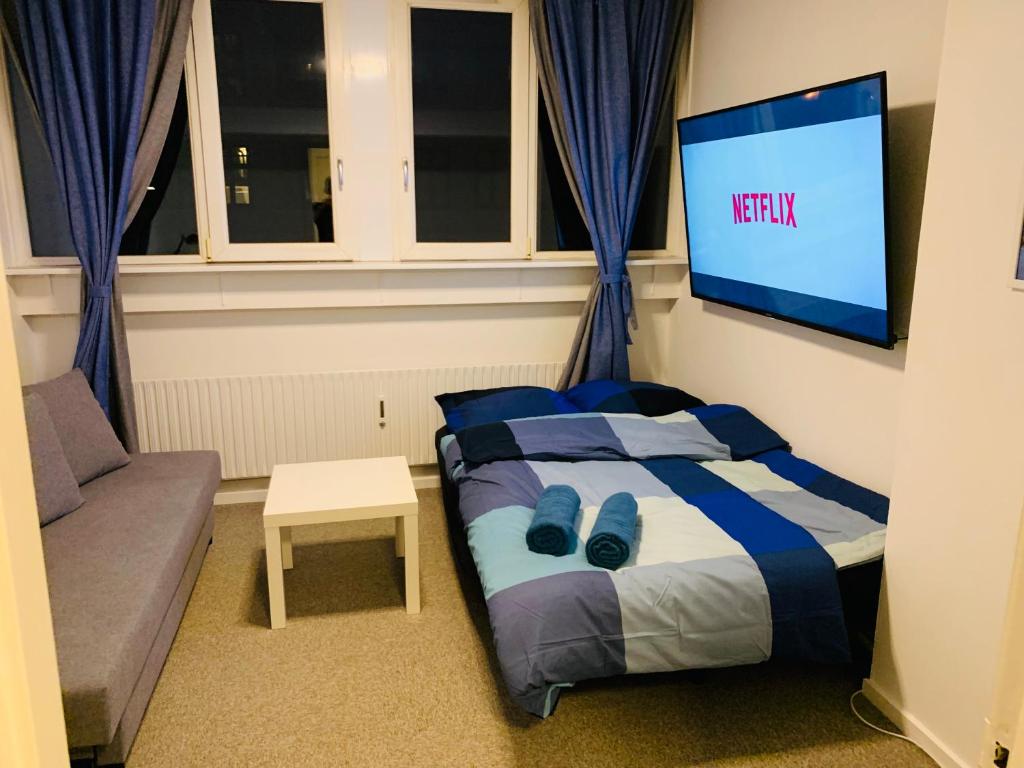 a bedroom with a bed and a tv on the wall at Central Studio + Free Bikes&Big Tv in Copenhagen