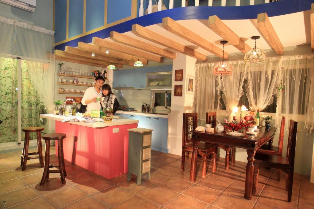 two people in a kitchen with a counter and a table at Happiness B&B in Luodong