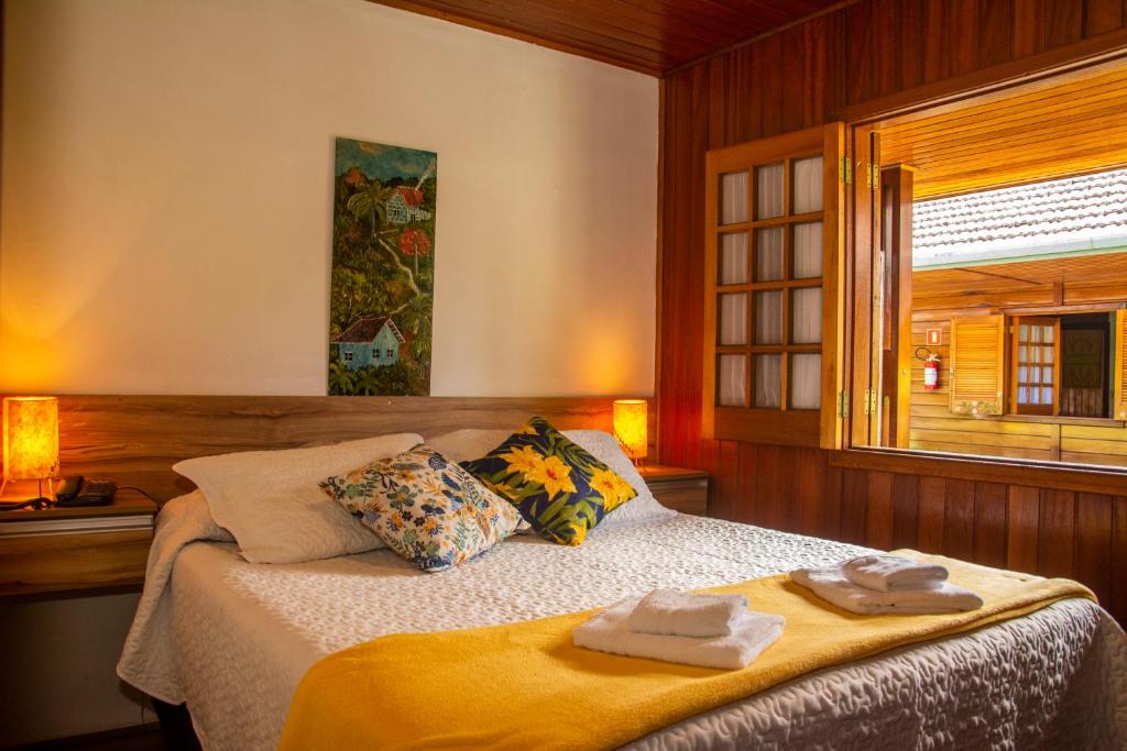 a bedroom with a bed with towels on it at Pousada Recanto Ninho Verde Chalés in Campos do Jordão