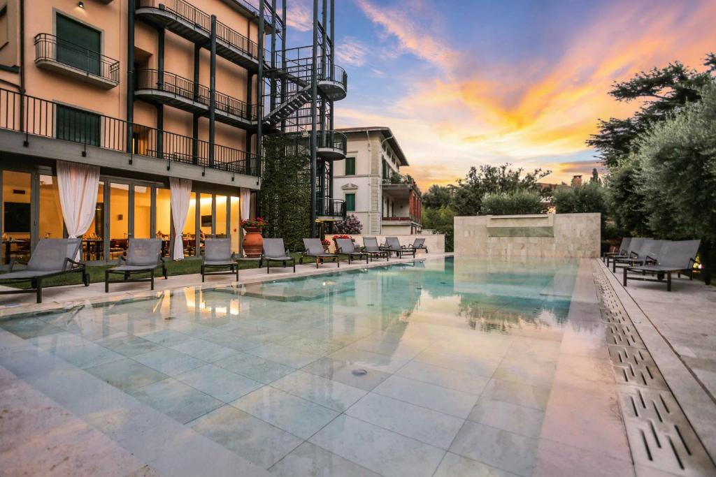 a swimming pool with chairs and a building at Grand Hotel Croce Di Malta in Montecatini Terme