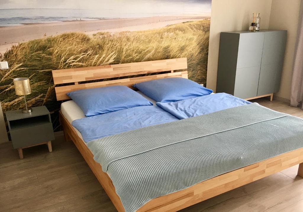 a bed with blue pillows and a painting of a beach at 2nd Home Appartements I in Nieder-Olm