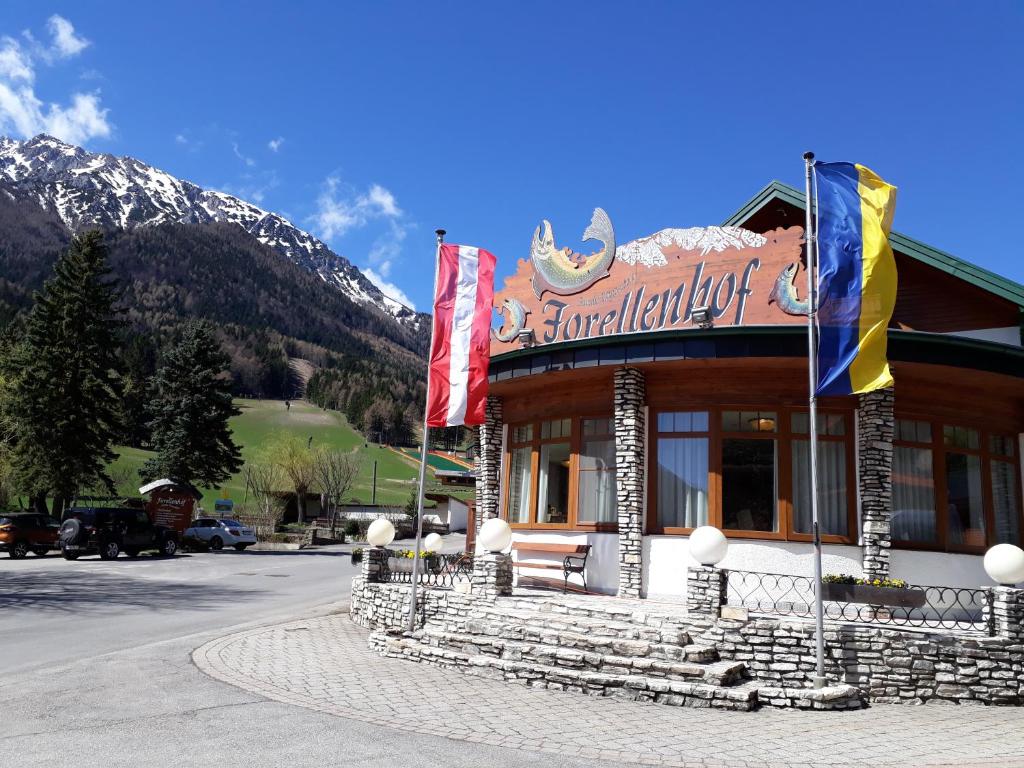 ein Gebäude mit Flaggen davor mit Bergen in der Unterkunft Hotel-Restaurant Forellenhof in Puchberg am Schneeberg