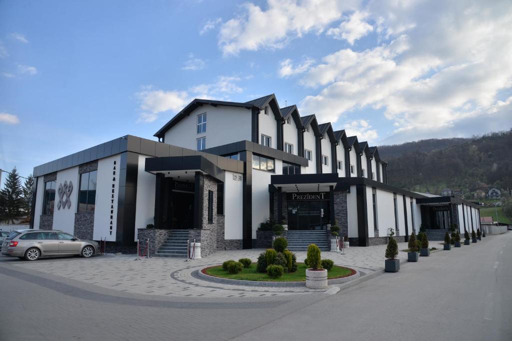 a building with a car parked in front of it at Hotel Prezident in Ivanjica