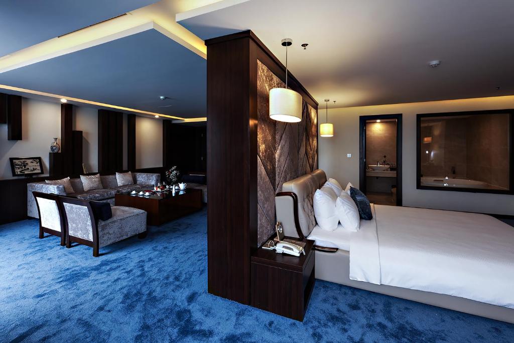 a hotel room with a bed and a living room at Central Luxury Hạ Long Hotel in Ha Long