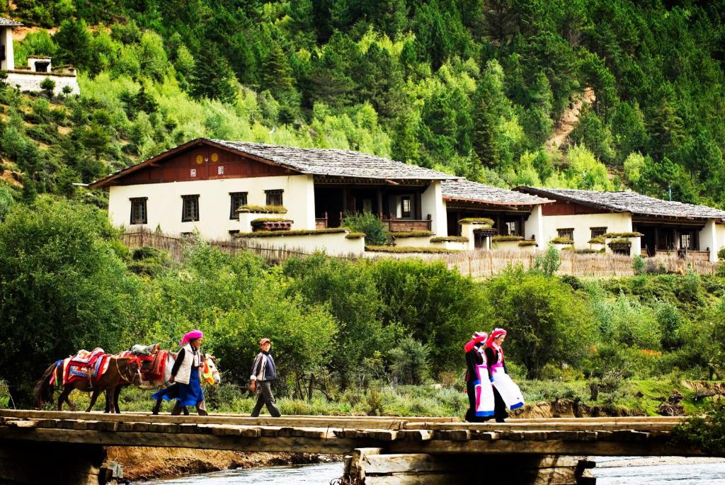 a group of people walking across a bridge at Banyan Tree Ringha in Shangri-La