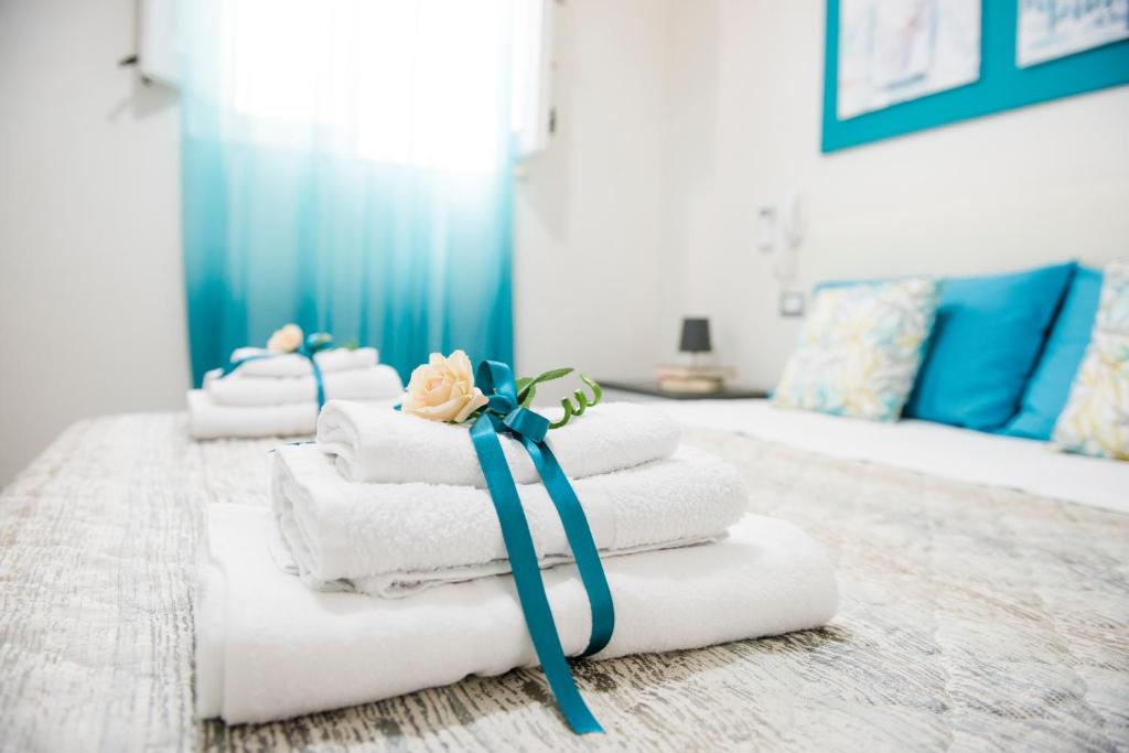 stos ręczników z niebieską wstążką i kwiatem na nich w obiekcie BENVENUTI AL SUD w mieście Castellammare del Golfo