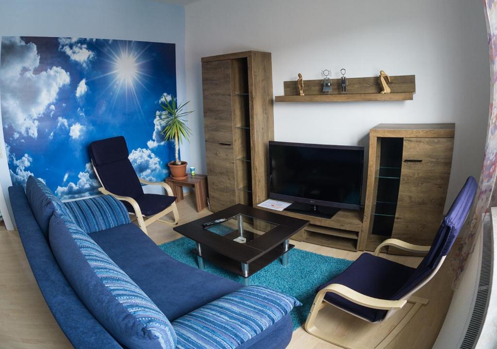 sala de estar con sofá azul y sillas en Ferienwohnung Wanderurlaub Thüringen, en Schmalkalden