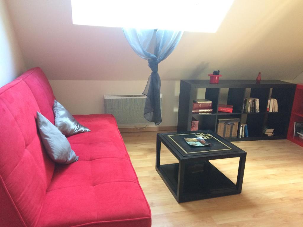sala de estar con sofá rojo y mesa en Gite les Camélias, en Sainte-Anne-sur-Vilaine