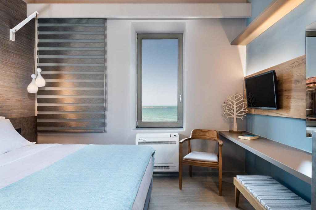 1 dormitorio con cama, escritorio y ventana en Ciel Collection Suites, en La Canea