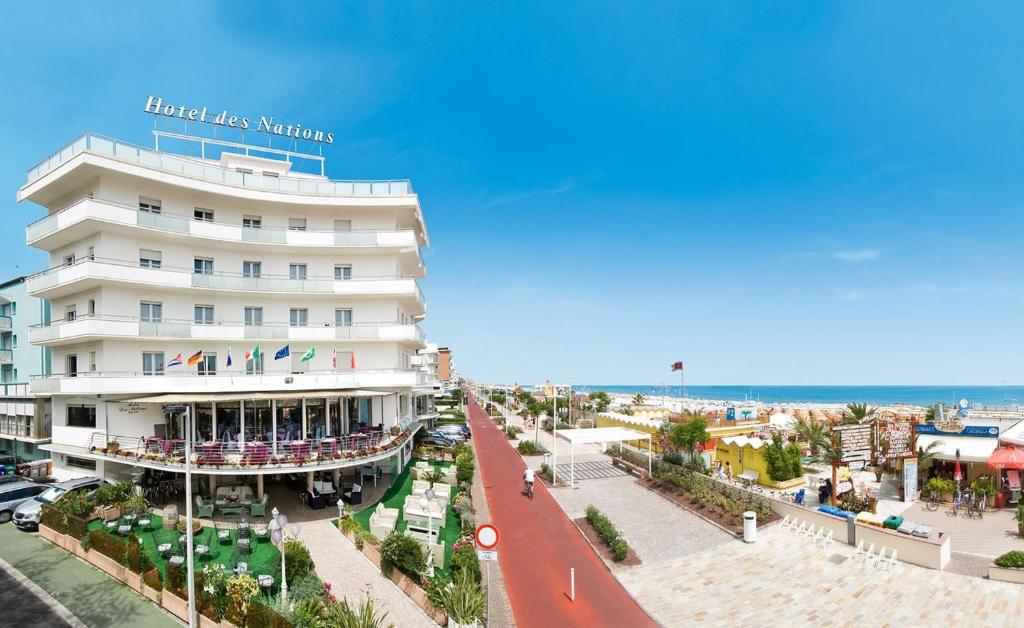 een groot wit gebouw in een straat naast een strand bij Hotel Des Nations - Vintage Hotel sul mare in Riccione