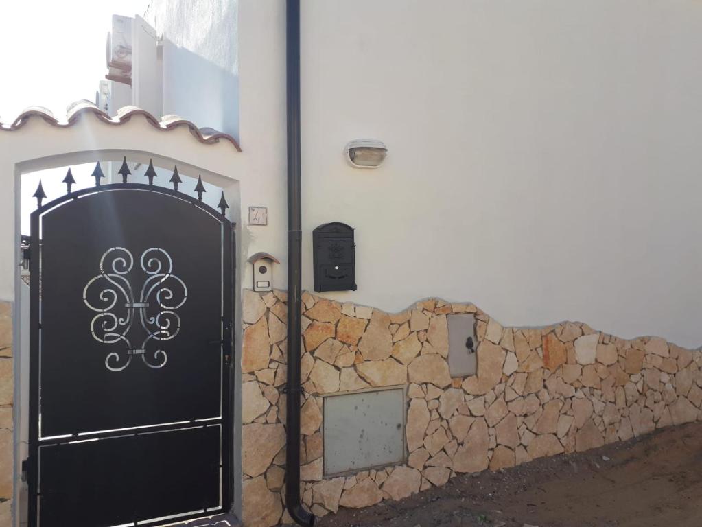 eine schwarze Tür an der Seite einer Steinmauer in der Unterkunft Calasetta casa al mare in Calasetta