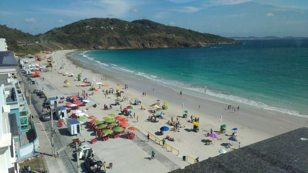 um grupo de pessoas em uma praia com guarda-sóis em Loft da prainha 117 em Arraial do Cabo