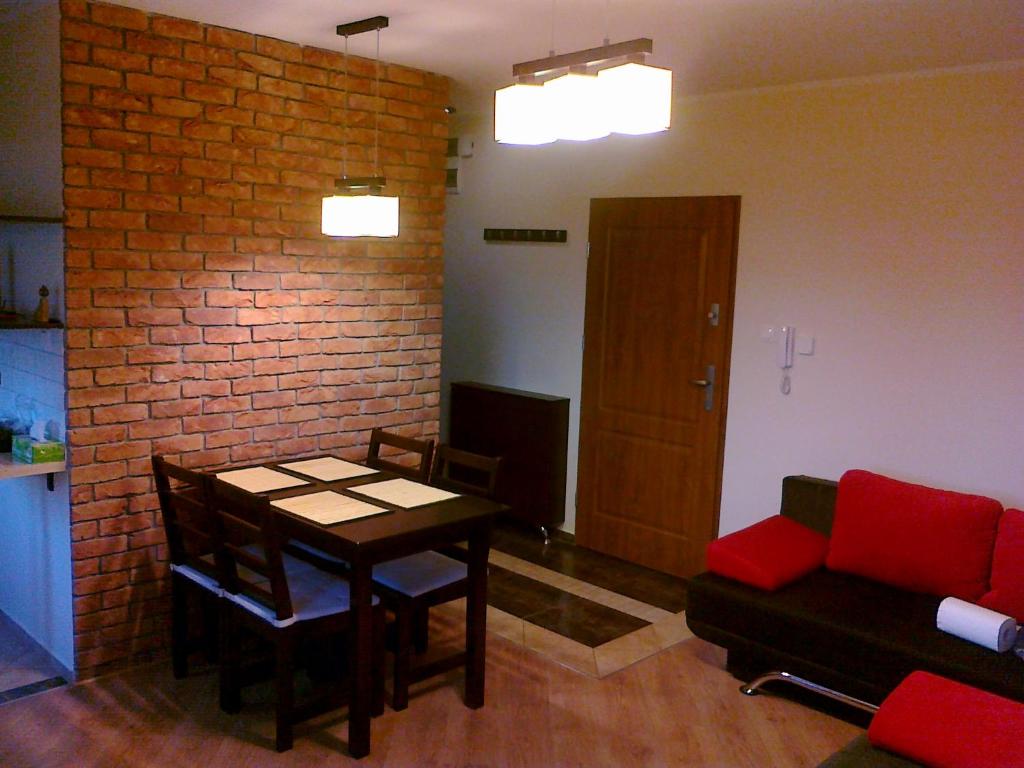 sala de estar con mesa y pared de ladrillo en Los Reyes en Krynica Morska