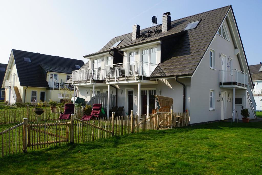 a white house with a fence in the yard at Ferienwohnung Baltic Sea in Börgerende-Rethwisch