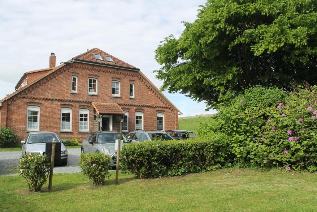 une maison en briques avec des voitures garées devant elle dans l'établissement Friesenstube, à Schweiburg