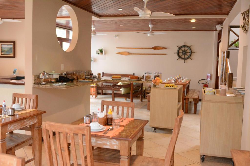 une cuisine et une salle à manger avec des tables et des chaises dans l'établissement Pousada Caiçara, à Abraão