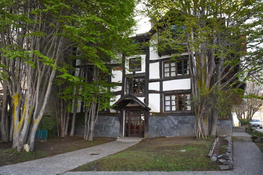 una casa en blanco y negro con árboles delante en Posada Del Fin Del Mundo en Ushuaia