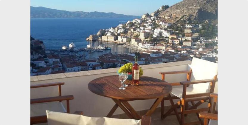 una mesa con una botella de vino y flores en el balcón en Hydra's View House, en Hydra