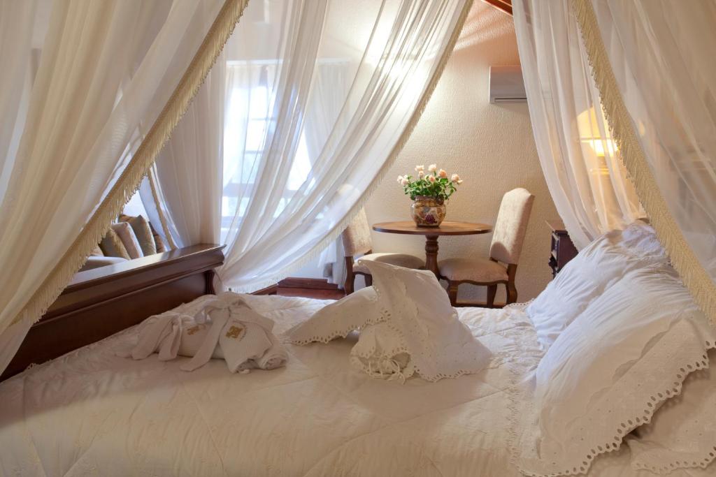 a bedroom with a white bed with a window at Hotel Pousada Florença in Gramado