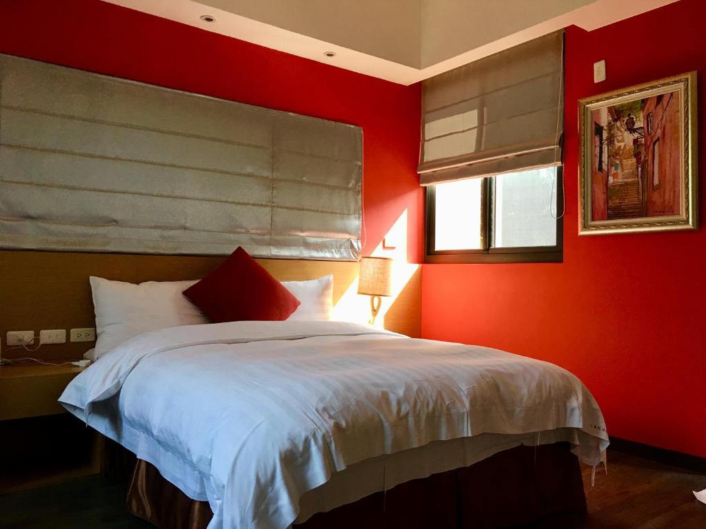 a bedroom with red walls and a bed with white sheets at Great Nature Villa in Jiji