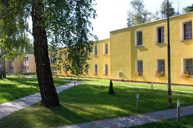 a large yellow building with a tree in front of it at Fala1 Ośrodek Wypoczynkowy in Gdańsk