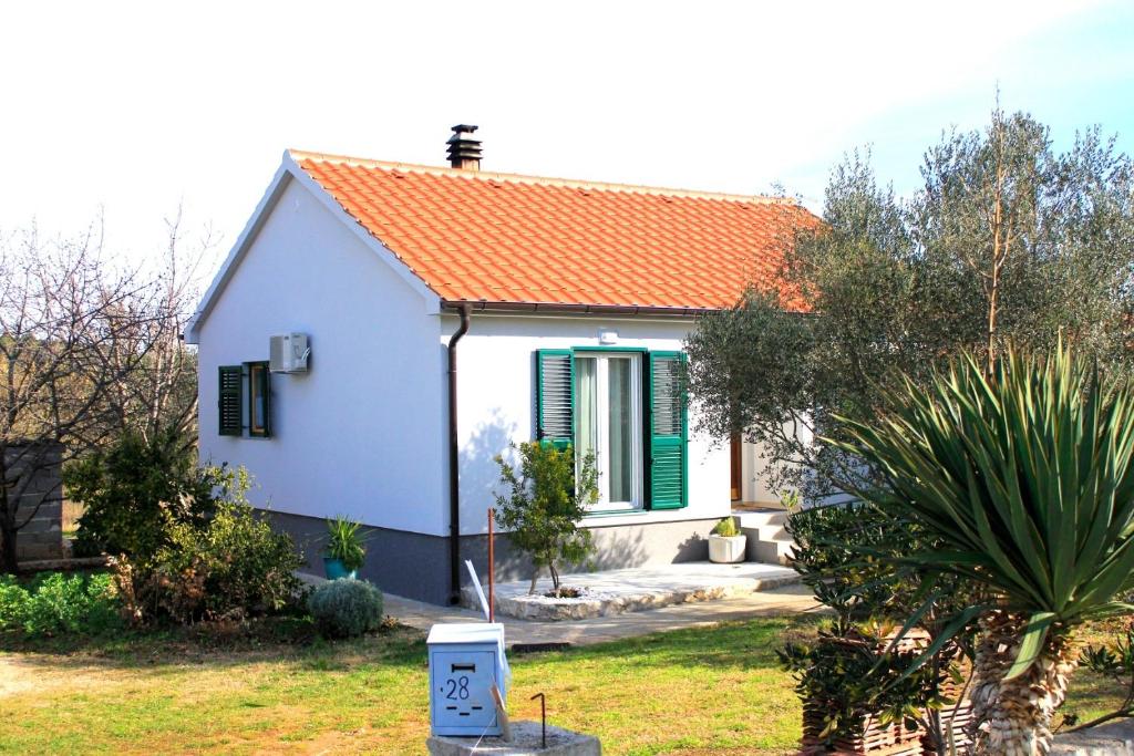 ein kleines weißes Haus mit orangefarbenem Dach in der Unterkunft Holiday home Pavica K in Pašman